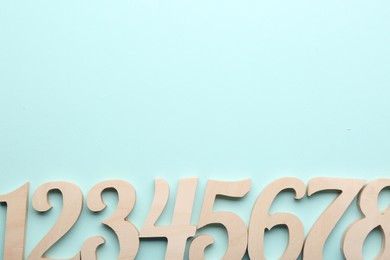 Wooden numbers on light background, flat lay. Space for text