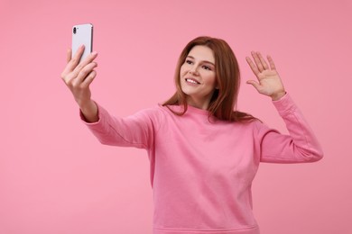 Beautiful woman taking selfie on pink background