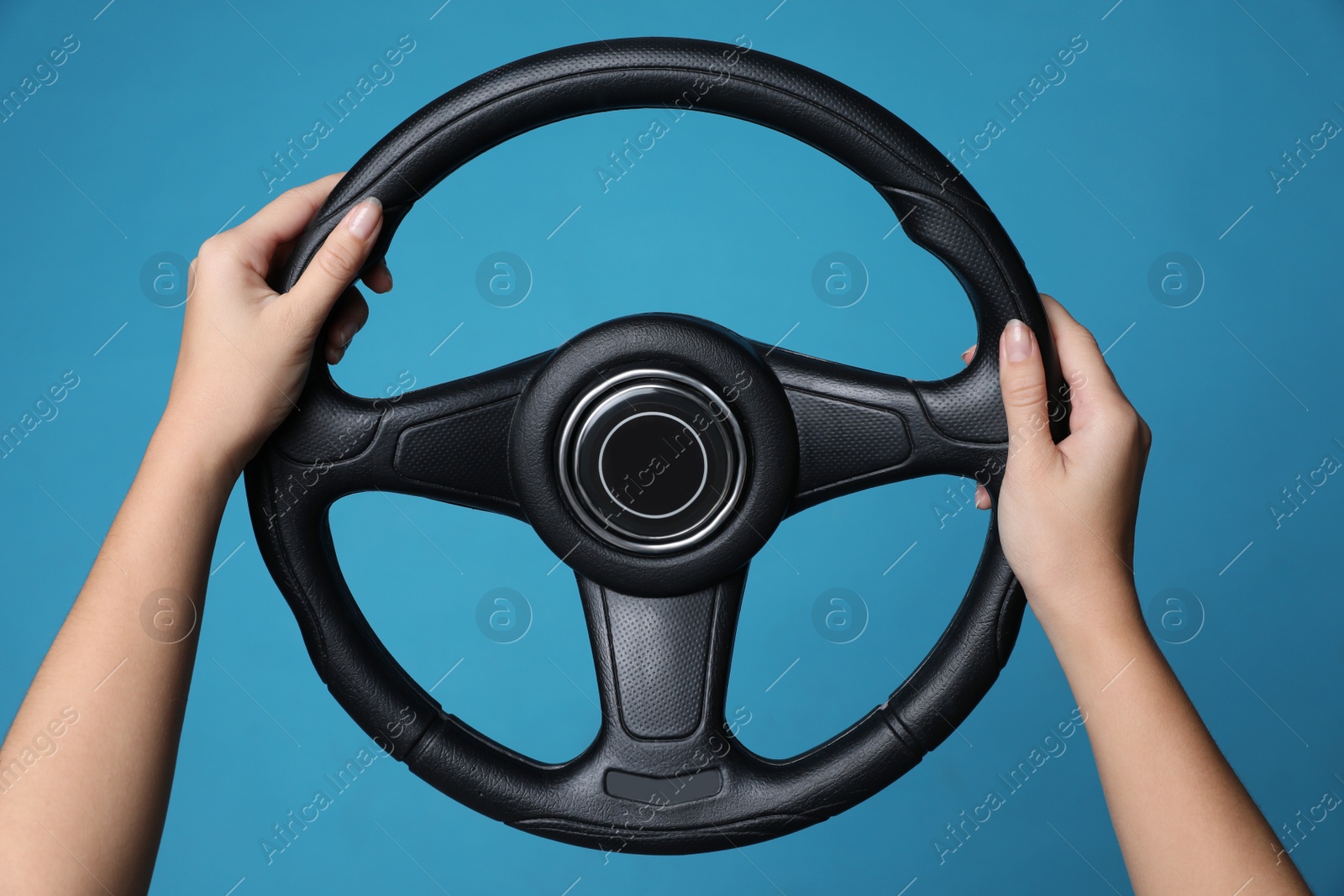 Photo of Woman holding steering wheel on blue background, closeup
