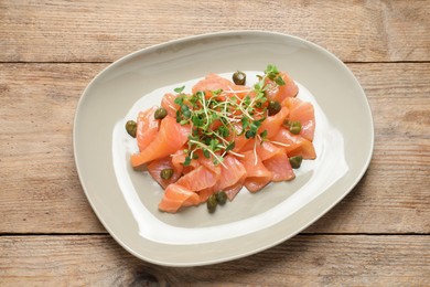 Photo of Delicious salmon carpaccio served on wooden table, top view