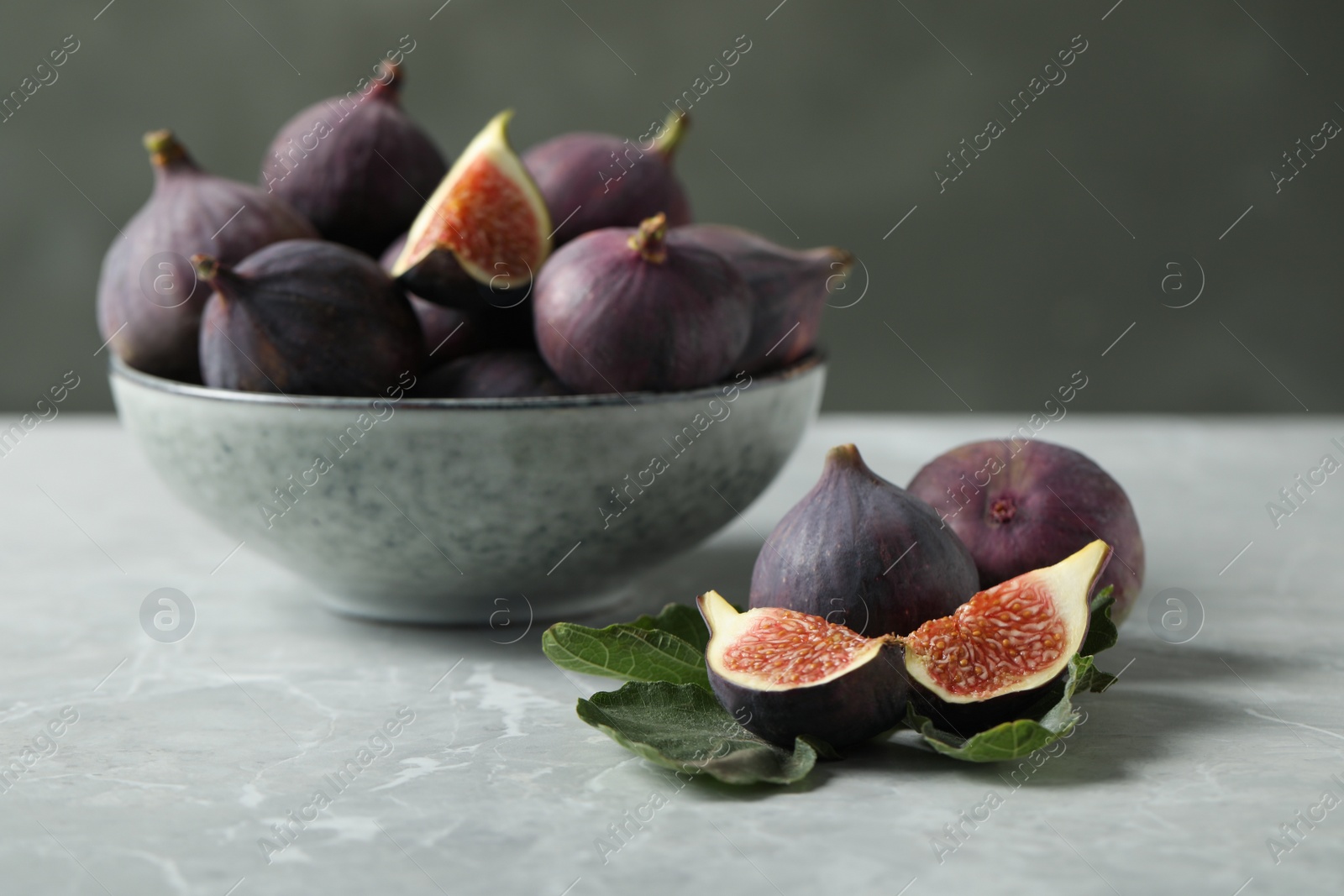Photo of Tasty raw figs on light grey marble table
