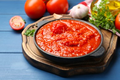 Photo of Homemade tomato sauce in bowl and ingredients on blue wooden table