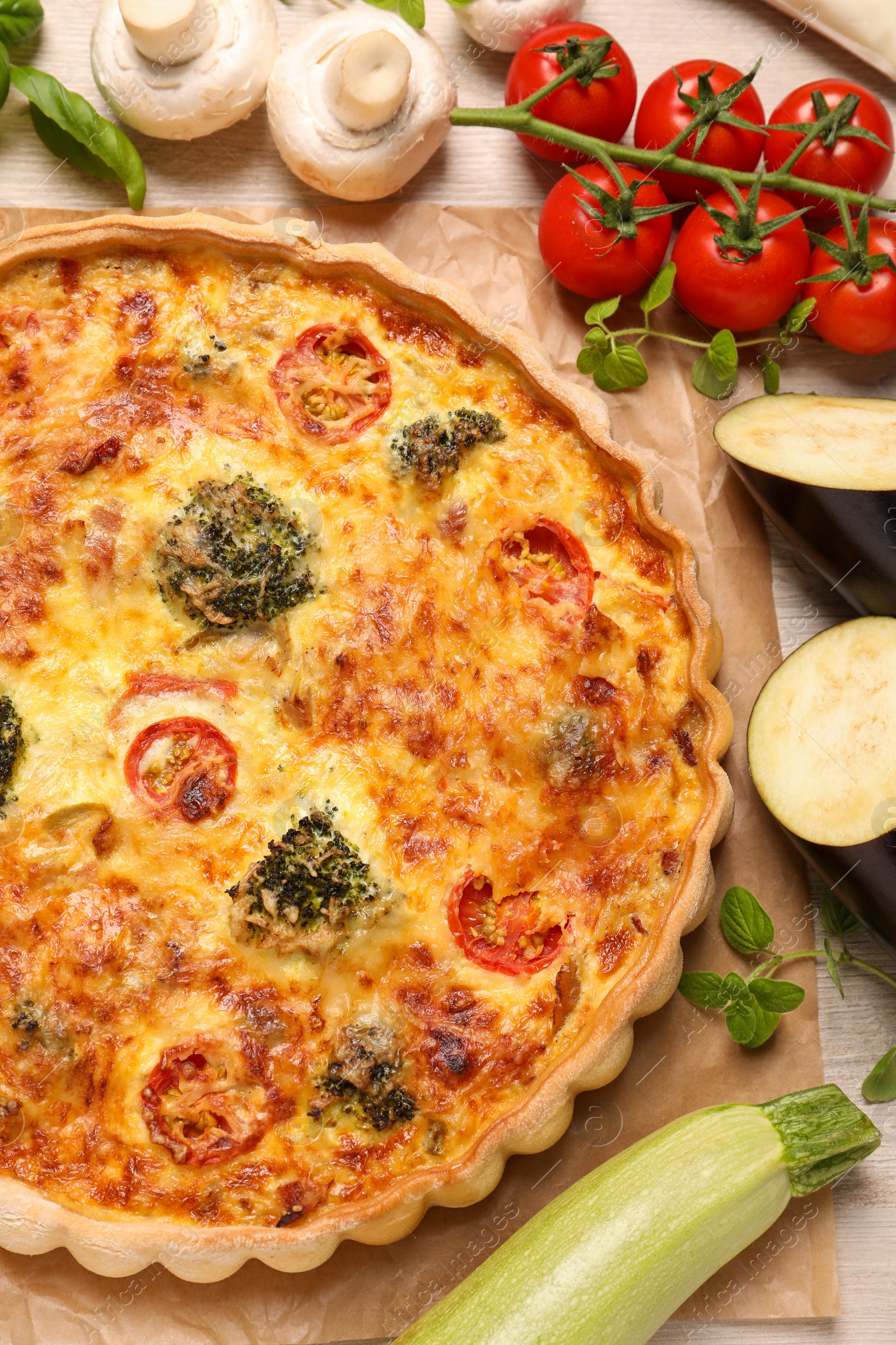 Photo of Delicious homemade vegetable quiche and ingredients on table, flat lay