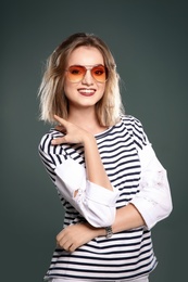 Beautiful young woman with sunglasses posing on color background