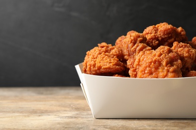 Photo of Tasty deep fried chicken pieces on wooden table, closeup. Space for text