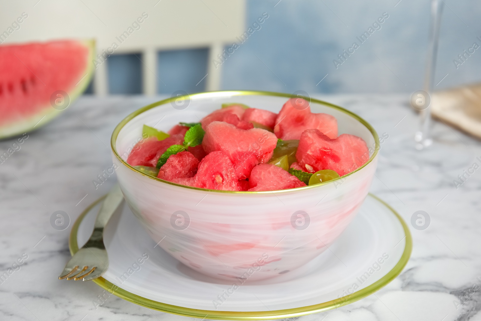 Photo of Delicious salad with watermelon on white marble table