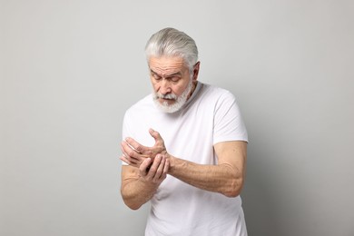 Photo of Arthritis symptoms. Man suffering from pain in wrist on gray background