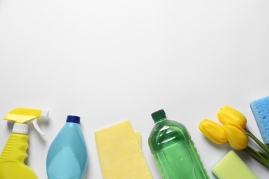 Spring cleaning. Detergents, flowers, sponges and rag on white background, flat lay. Space for text