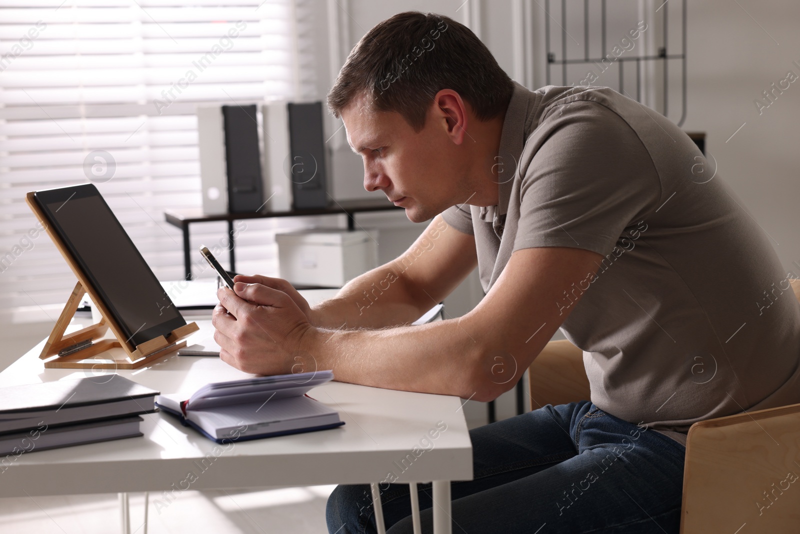 Photo of Man with bad posture using smartphone in office