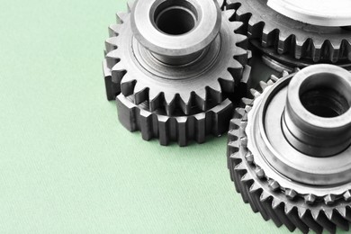 Photo of Different stainless steel gears on light green background, closeup. Space for text