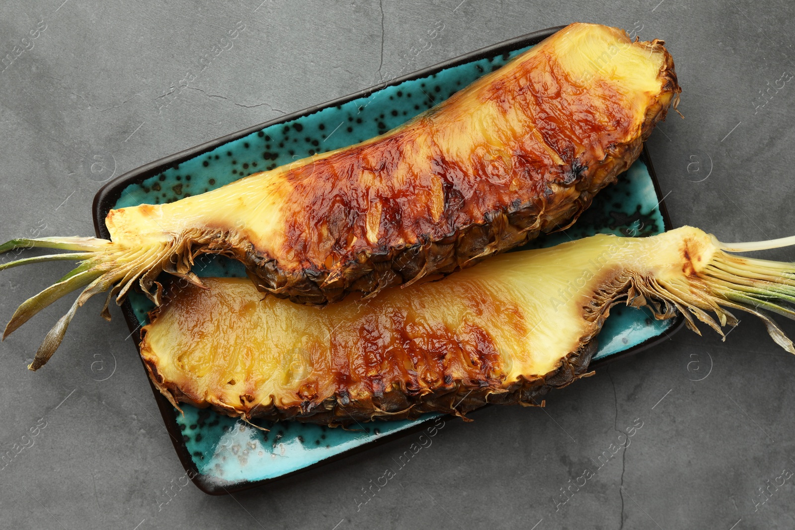Photo of Tasty grilled pineapple pieces on grey textured table, top view
