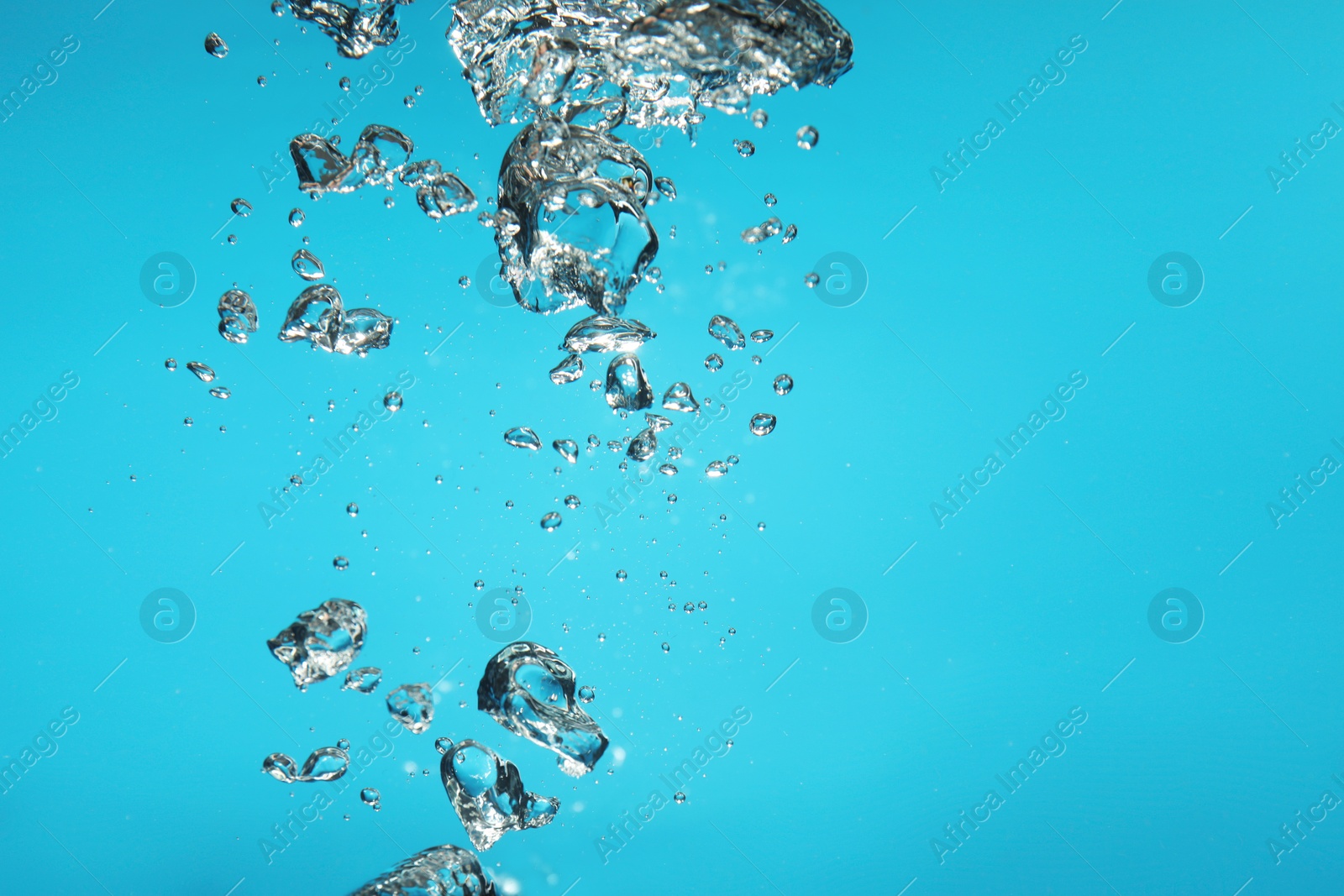 Photo of Air bubbles in water on light blue background. Space for text