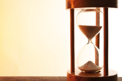 Hourglass with flowing sand on table against light background. Time management