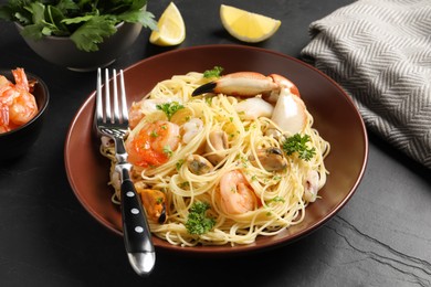 Photo of Delicious pasta with sea food served on black table