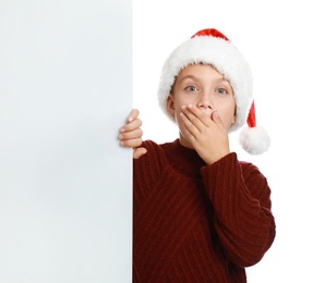 Photo of Emotional child in Santa hat with blank banner on white background. Christmas celebration
