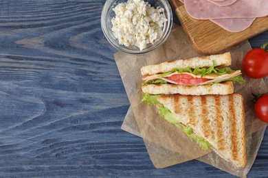 Photo of Tasty sandwich with ham on blue wooden table, flat lay. Space for text