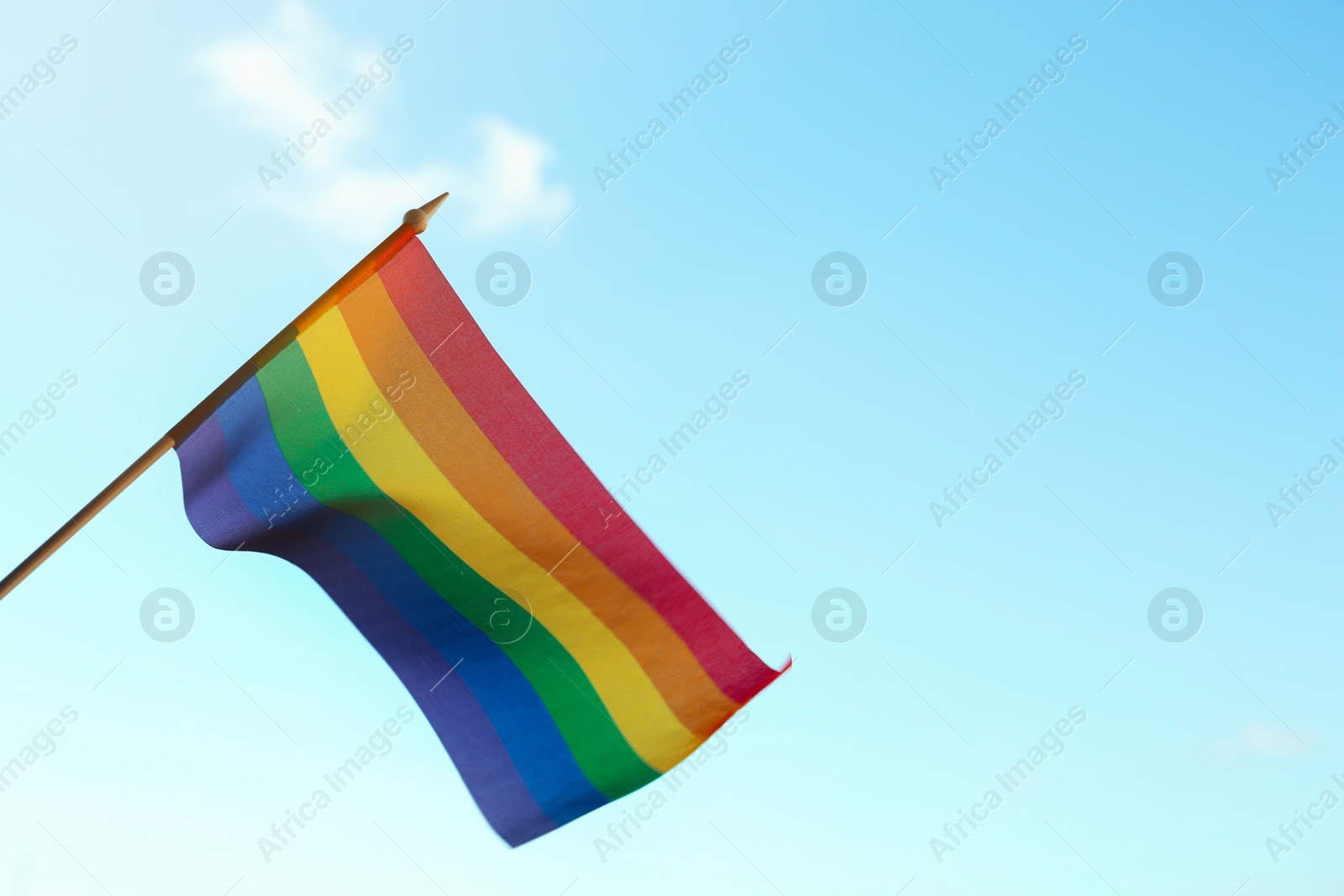 Photo of Bright LGBT flag against blue sky. Space for text