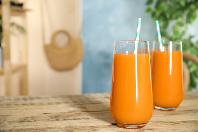 Freshly made carrot juice on wooden table, space for text