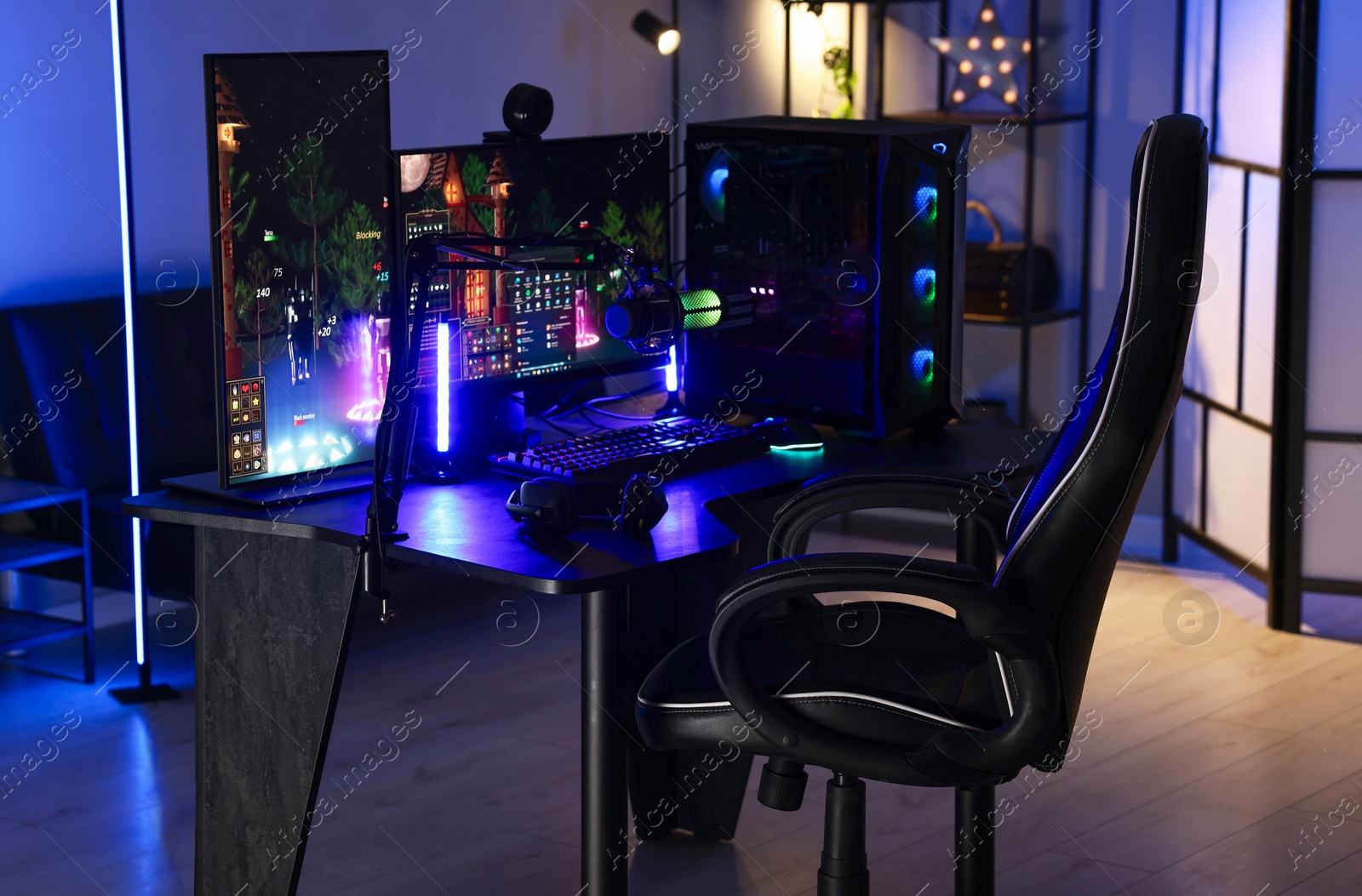 Photo of Playing video games. Stylish room interior with modern computer and gaming chair in neon lights