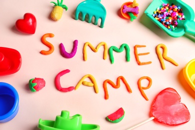 Photo of Composition with words SUMMER CAMP made from modelling clay and beach toys on color background