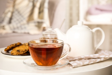 Photo of Cup of hot tea on white table indoors. Winter drink