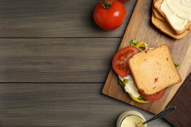 Photo of Delicious sandwich with vegetables and mayonnaise served on wooden table, flat lay. Space for text