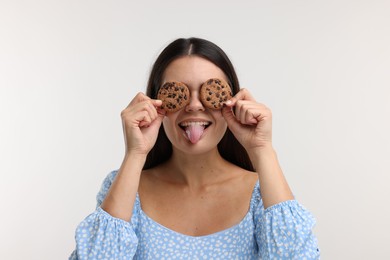 Photo of Young woman with chocolate chip cookies on white background