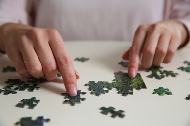 Photo of Young woman playing with puzzles at table, closeup