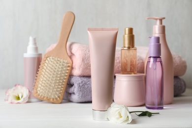 Photo of Composition with hair products and flowers on white wooden table
