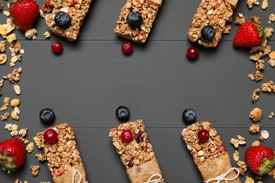 Photo of Tasty granola bars and ingredients on grey wooden table, flat lay. Space for text