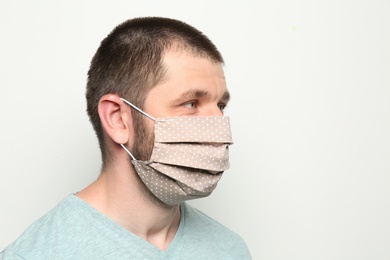 Photo of Man wearing handmade cloth mask on white background, space for text. Personal protective equipment during COVID-19 pandemic