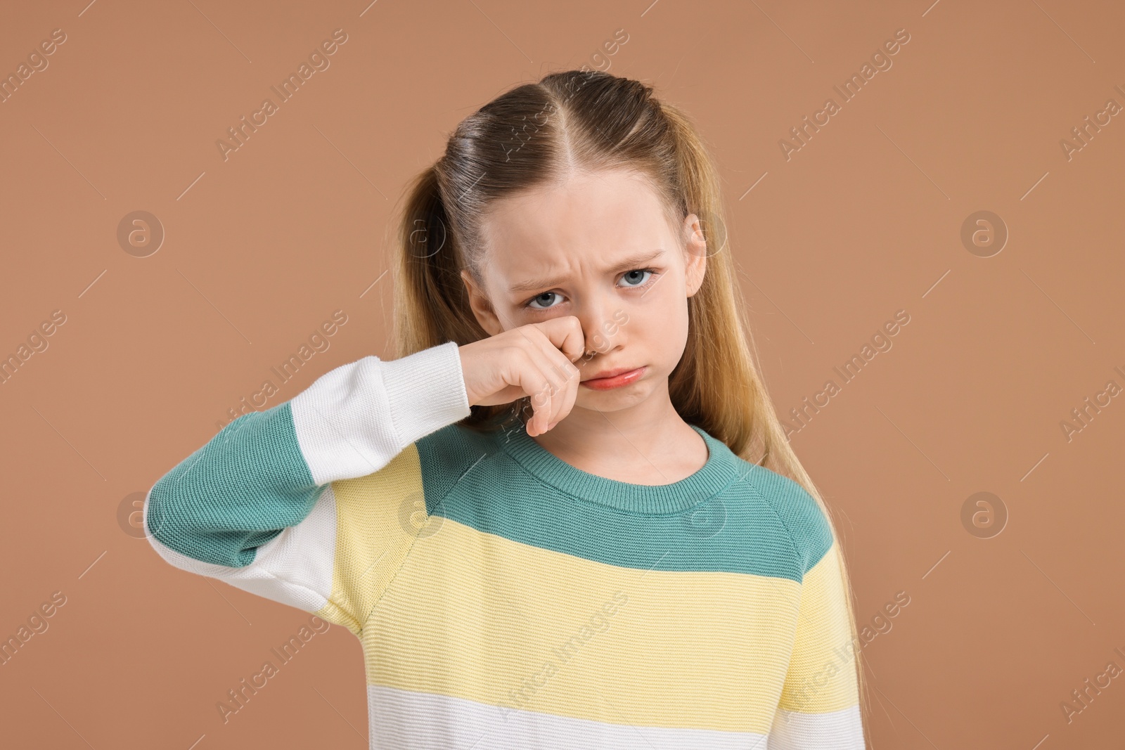 Photo of Portrait of sad girl on light brown background