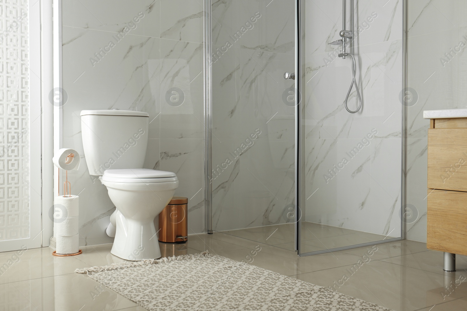 Photo of Toilet bowl near shower stall in modern bathroom interior