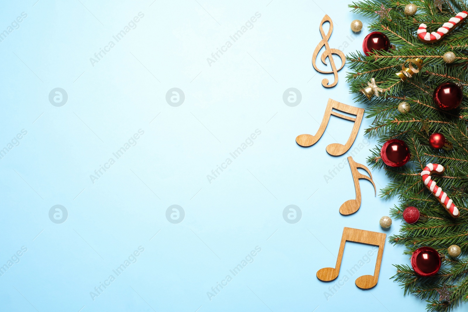 Photo of Flat lay composition with Christmas decor and music notes on light blue background, space for text