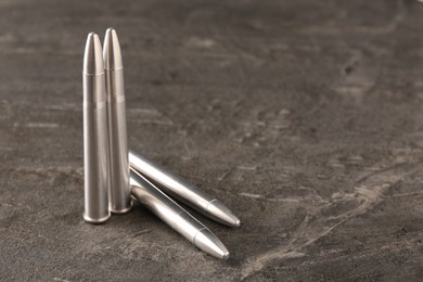 Metal bullets on dark textured table, space for text