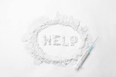 Photo of Word HELP written with cocaine and syringe on white background, top view