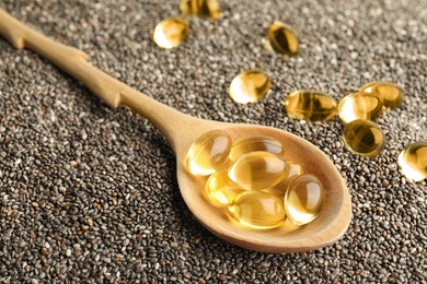 Spoon with oil capsules on chia seeds, closeup