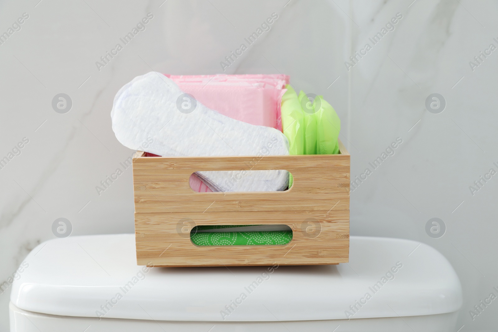 Photo of Organizer with different feminine hygiene products on toilet bowl in bathroom