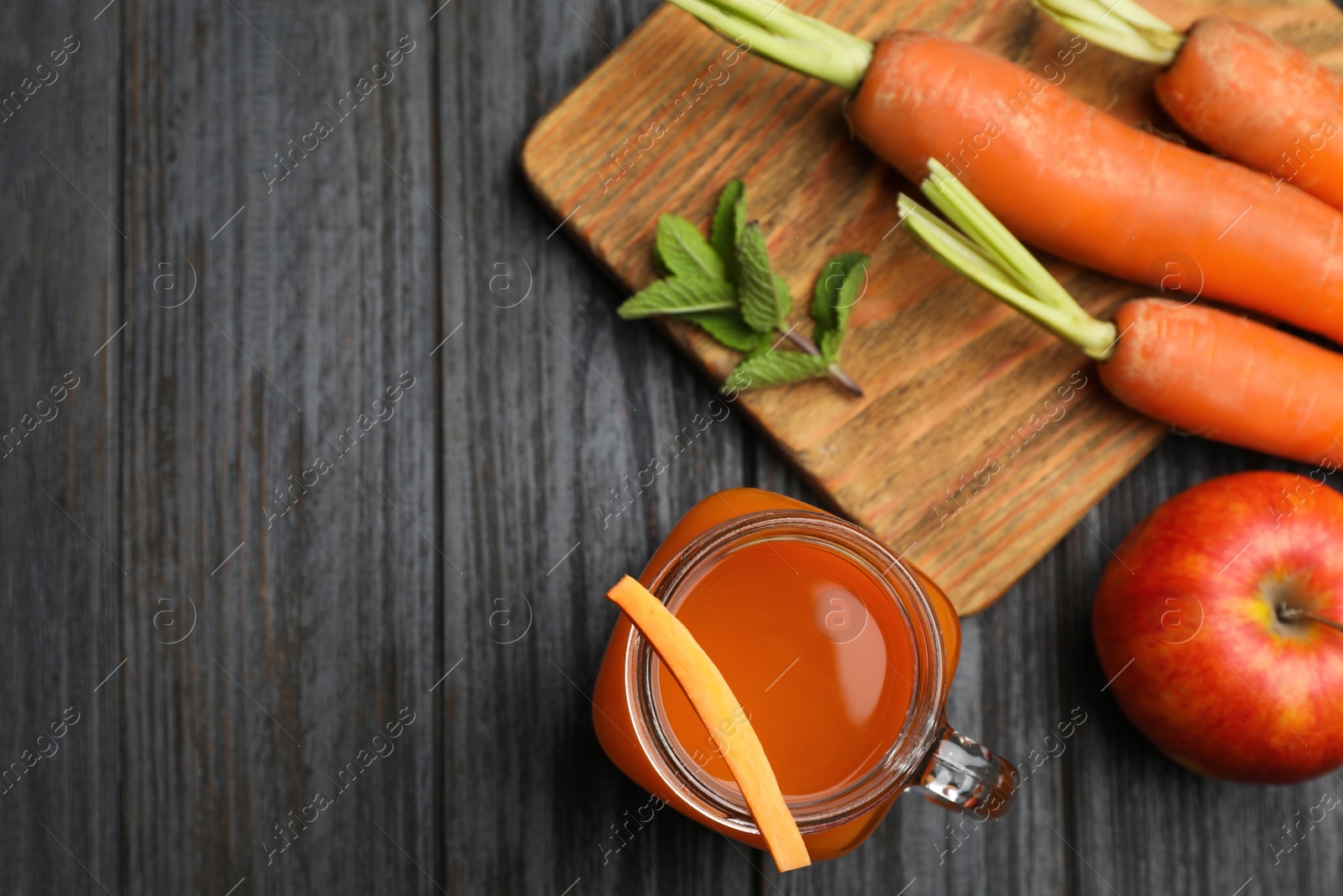 Photo of Flat lay composition with mason jar of carrot drink on wooden table, space for text