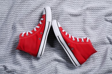 Pair of new stylish red sneakers on light grey fabric, flat lay