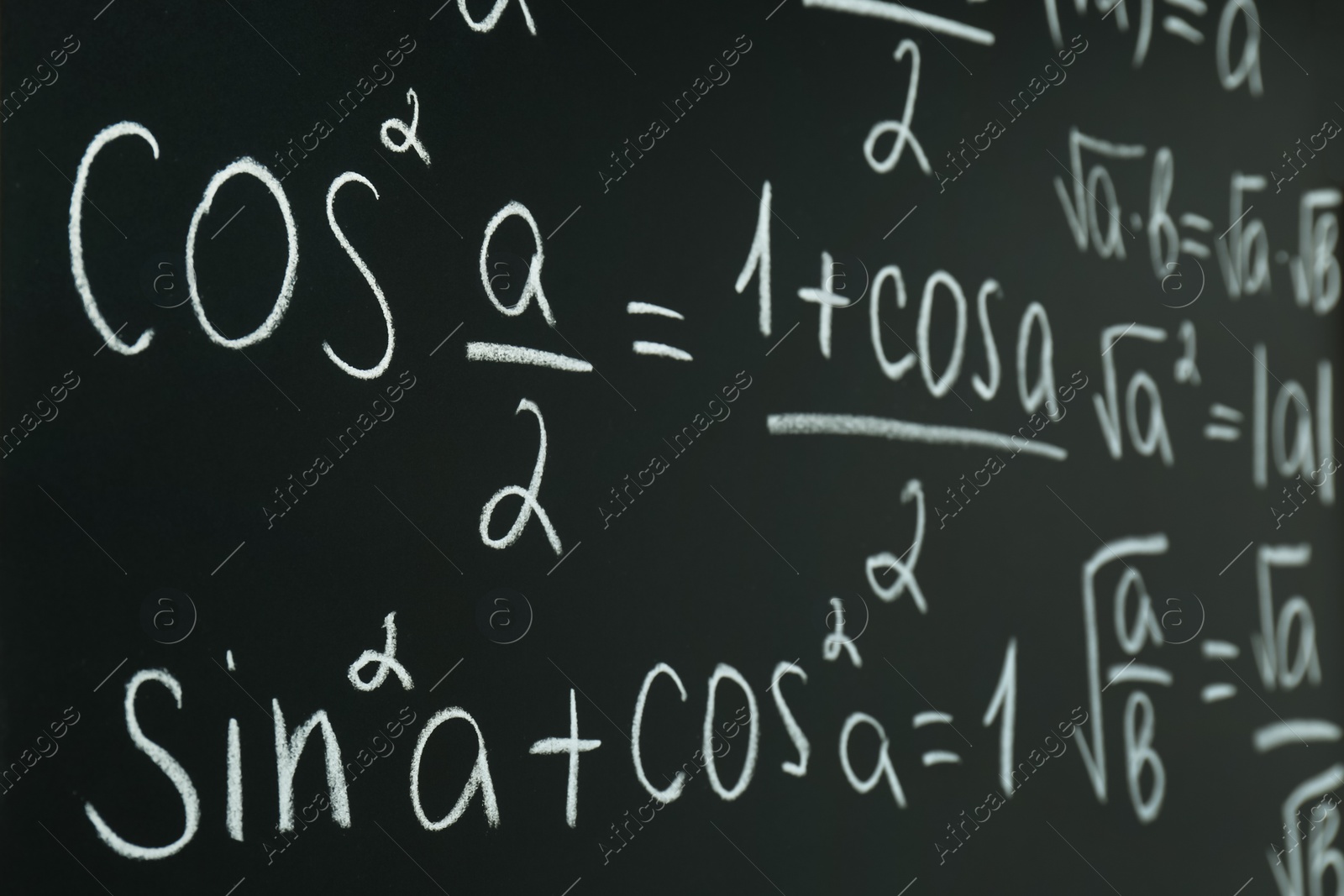 Photo of Different mathematical formulas written with chalk on blackboard, closeup