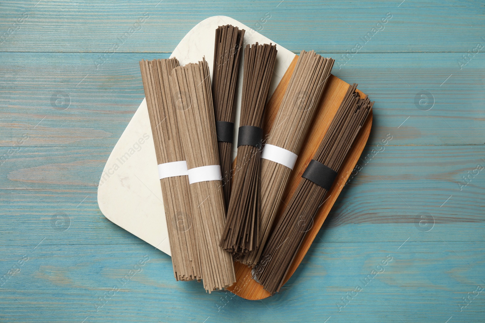 Photo of Uncooked buckwheat noodles (soba) on light blue wooden table, top view