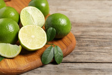 Photo of Fresh ripe limes on wooden table, closeup. Space for text