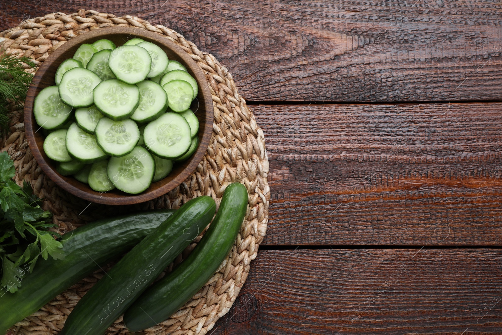 Photo of Fresh ripe cucumbers, dill and parsley on wooden table, top view. Space for text