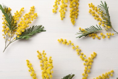 Beautiful mimosa flowers on white wooden table, flat lay