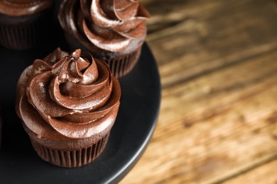 Photo of Dessert stand with delicious chocolate cupcakes on wooden table, closeup. Space for text