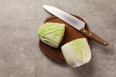 Photo of Halves of fresh Chinese cabbage and knife on light grey table, top view