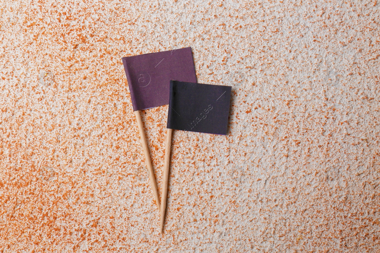 Photo of Black paper flags on color textured background, flat lay