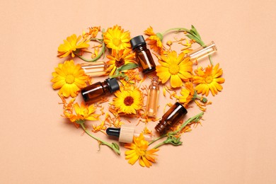 Heart made of bottles with essential oils and beautiful calendula flowers on beige background, flat lay