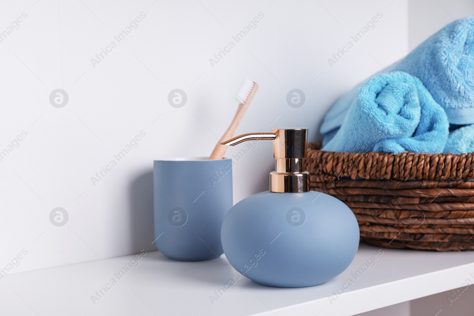 Photo of Stylish soap dispenser, holder with toothbrush and towels on shelf